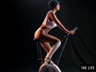 Stevig zweterig tiener bespringen een exercise bike zetel.